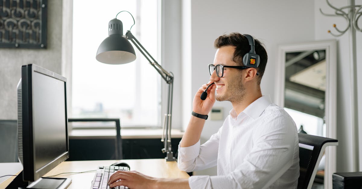 A Smiling Man Wearing a Headset Looking at His Computer Screen