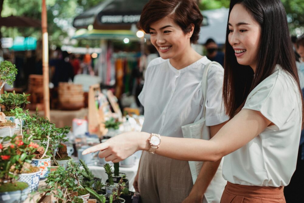 Crop happy Asian women choosing houseplants in market